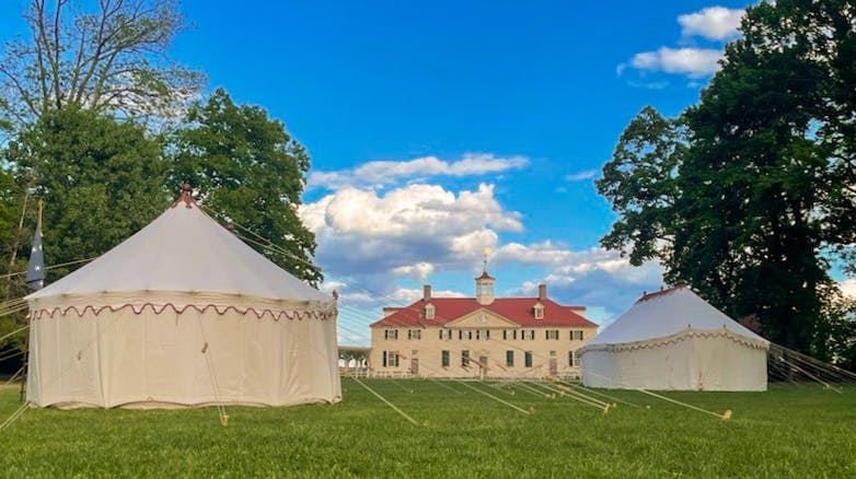 The Museum's replica George Washington headquarters tents set up on Mount Vernon's lawn with the mansion in the background.