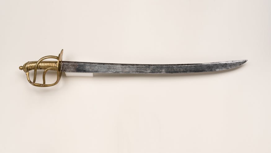This image shows a French Naval Cutlass against a white background. The hilt of the cutlass is gold and on the left hand side of the image.