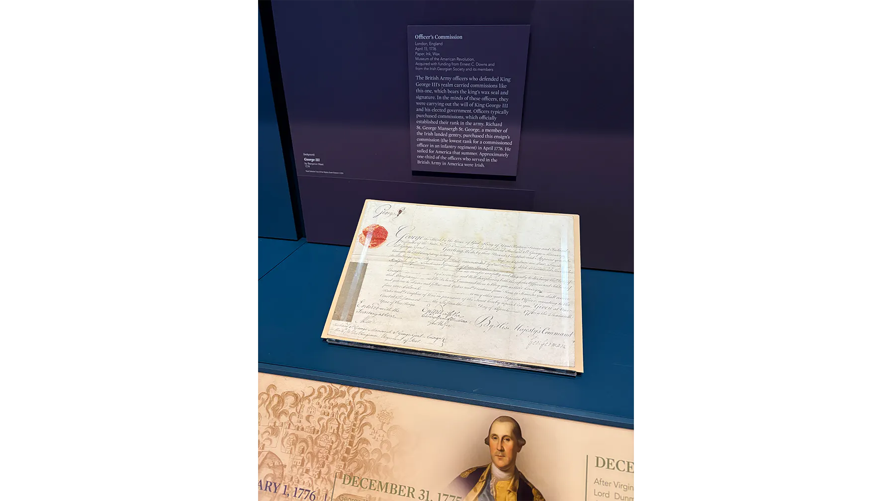 A document with a small red wax seal in the upper left corner propped in a case