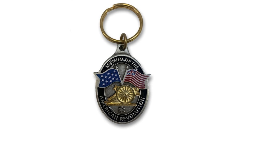 Keychain featuring a cannon in the middle of Washington's 13-star standard and an early American flag.