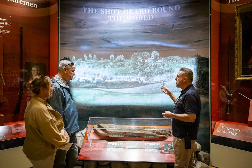 A Museum educator talks to two guests about the Shot Heard Round the World at the Battles of Lexington and Concord that started the Revolutionary War.