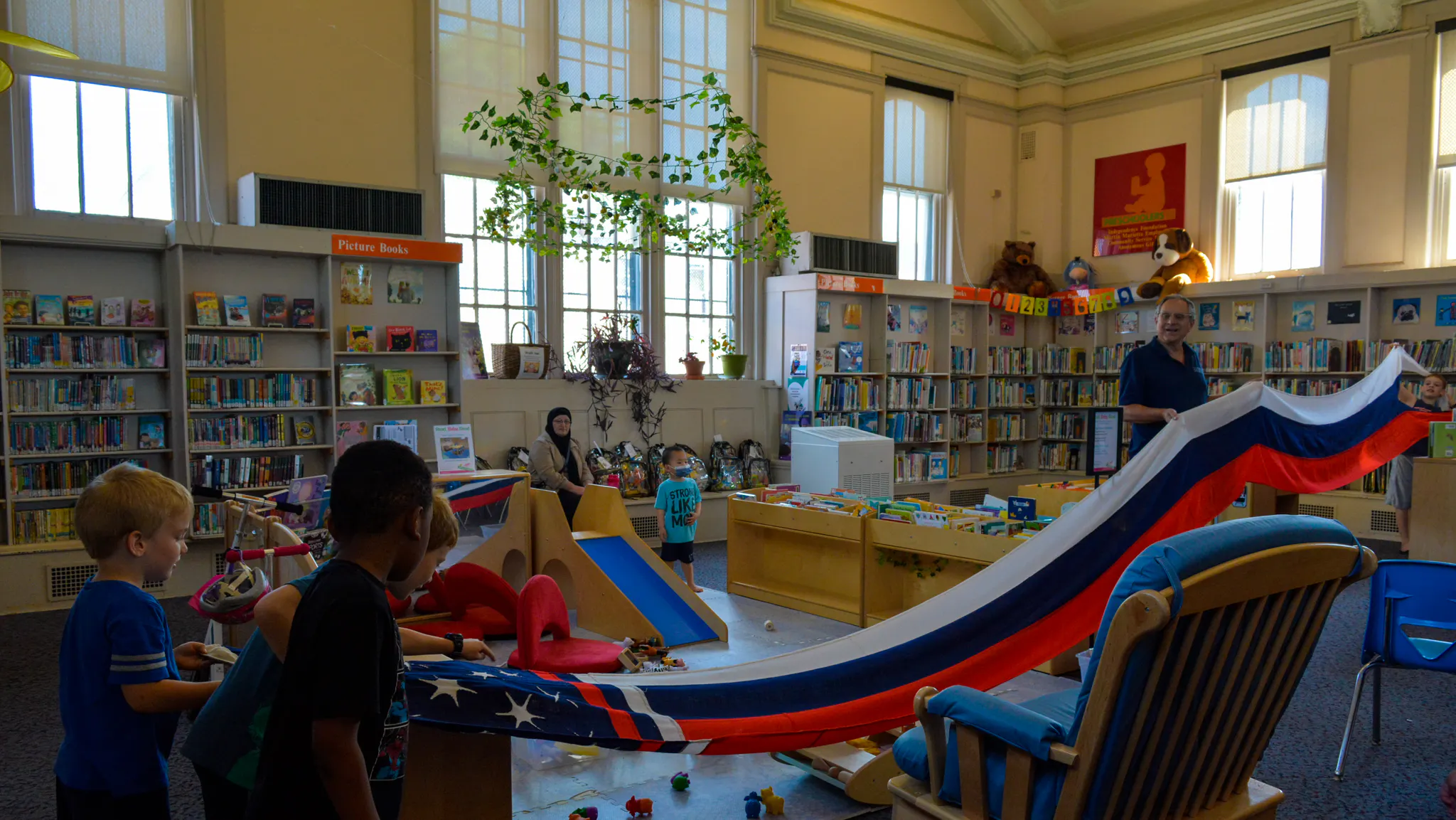 Young kids interact with a red, white, and blue flag