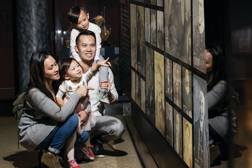 A family of four view The Revolution's Veterans picture wall in the Museum galleries.