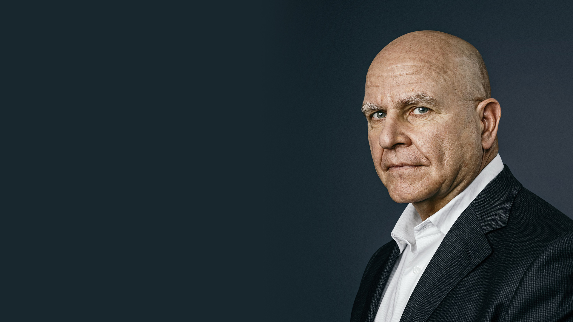 A bald white man in a dark suit and white shirt