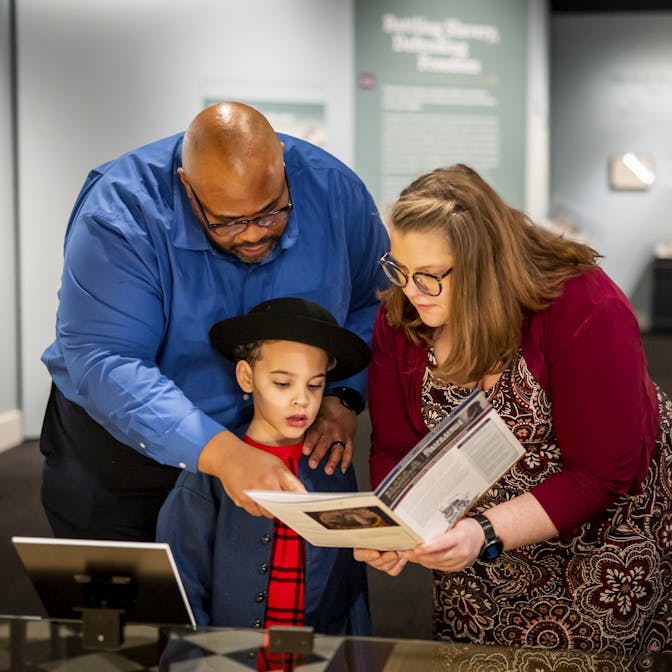 A family looks at the family guide activities in the Museum's Black Founders exhibit.