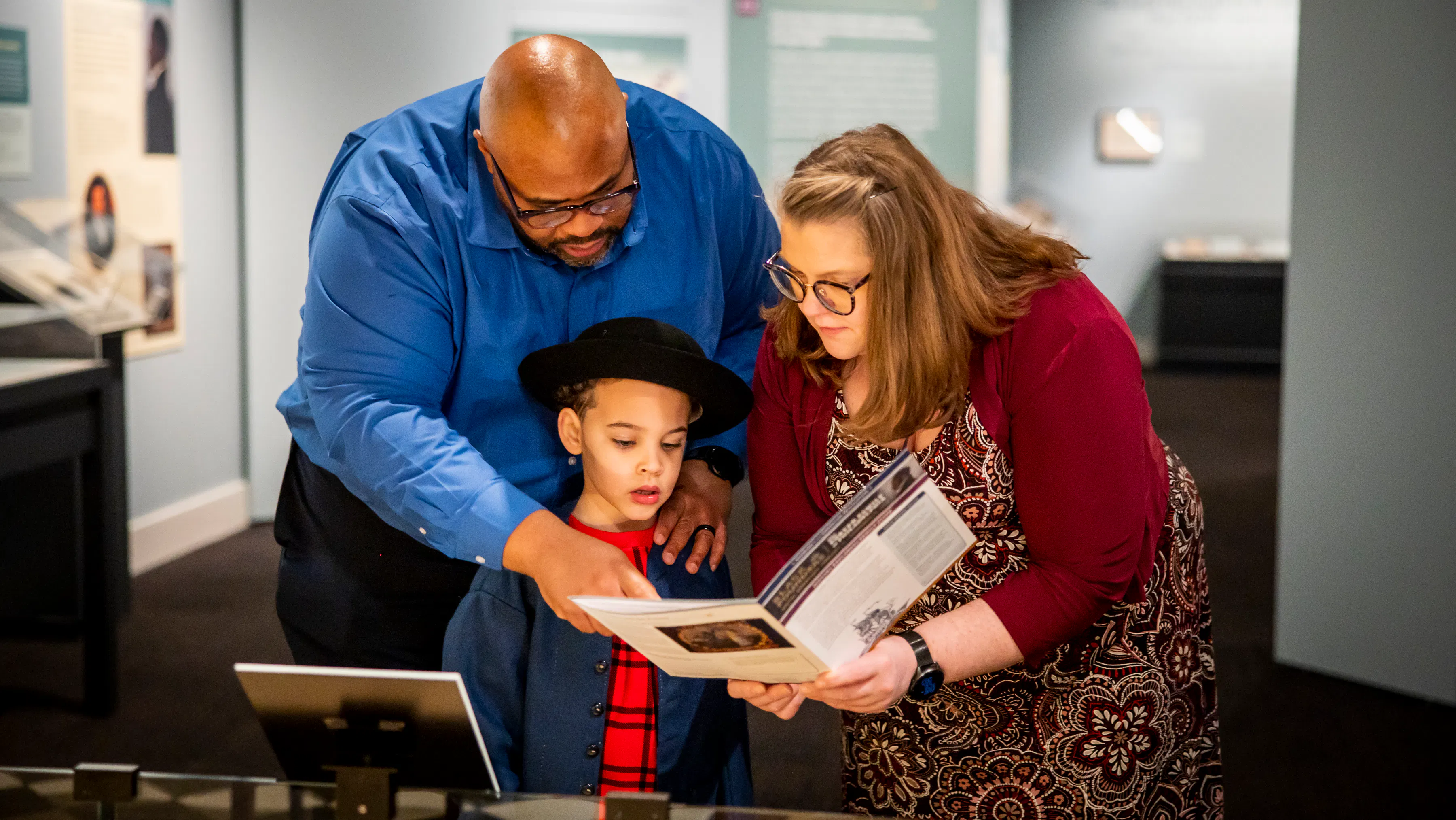 A family looks at the family guide activities in the Museum's Black Founders exhibit.