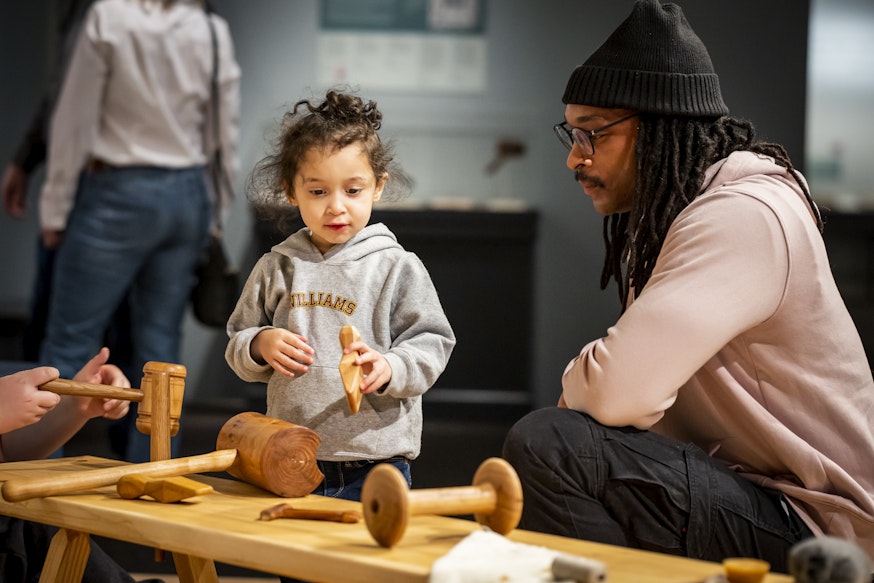 A family uses replica tools in a recreated sail loft in the Museum's Black Founders exhibit.