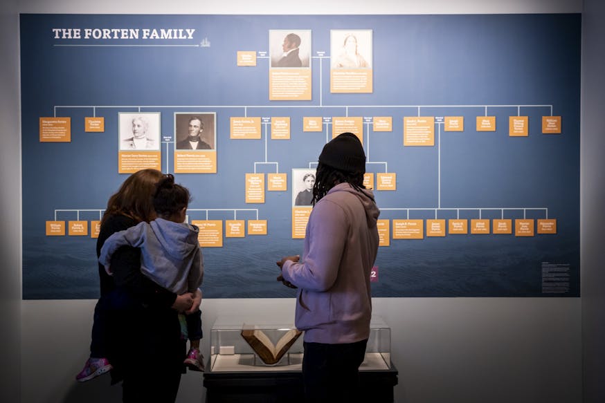 A family views the Forten family tree and family bible in the Museum's Black Founders exhibit.