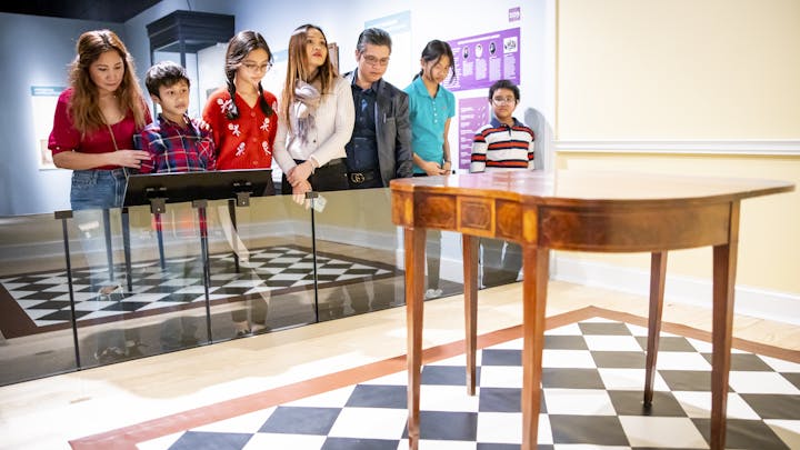 A family looks at a table passed down through the Forten family in the Museum's Black Founders exhibit.