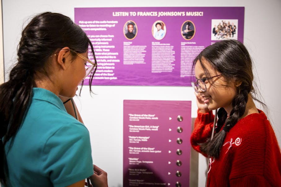 Two young visitors listen to the music of Francis Johnson at a listening station in the Museum's Black Founders exhibit.