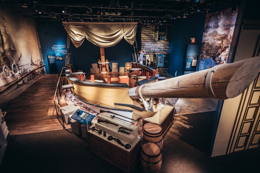 A high up view of the War at Sea gallery in the Museum of the American Revolution featuring a sloop