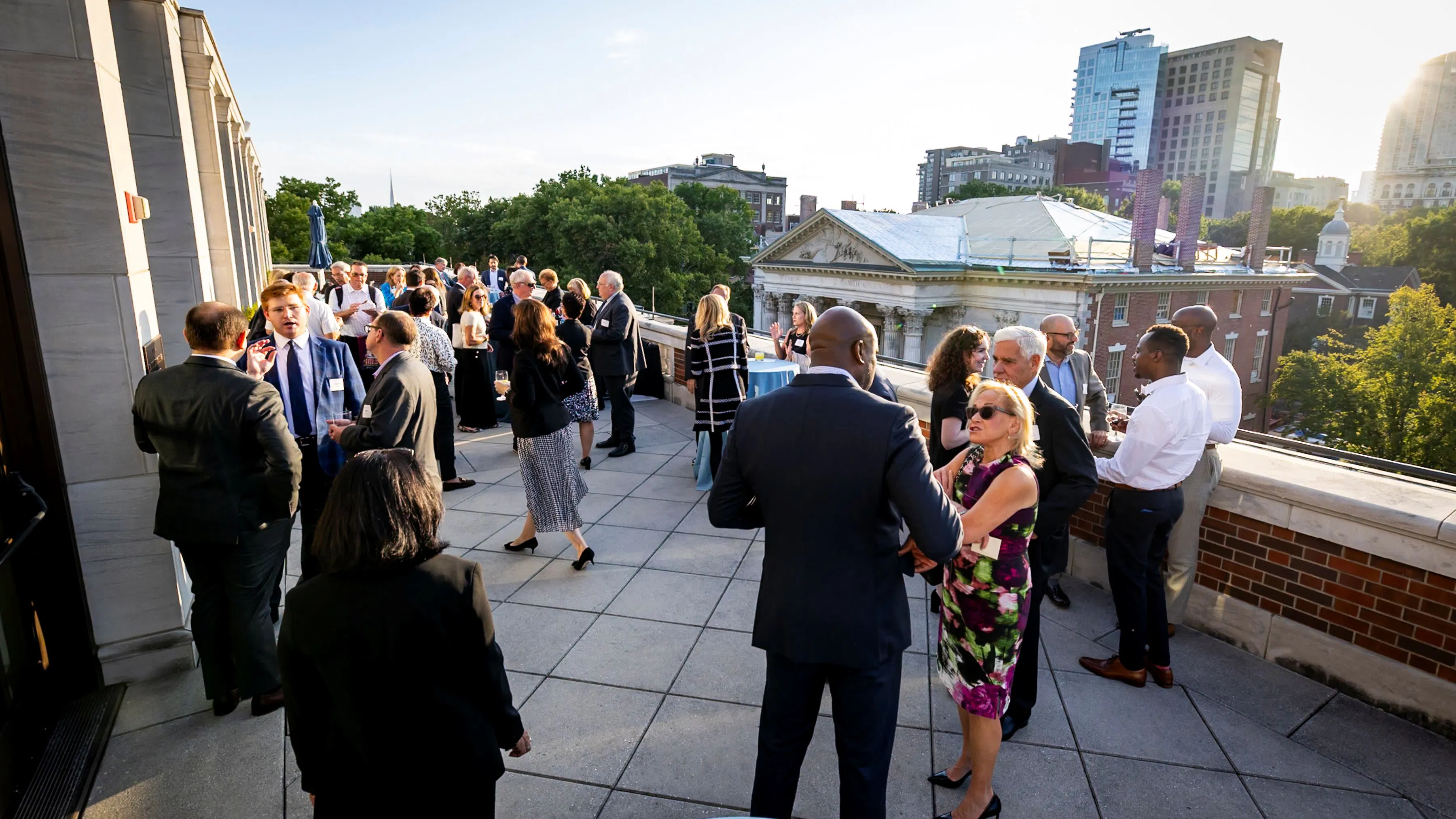 A group of people on an outdoor terrace, with the city skyline in the background