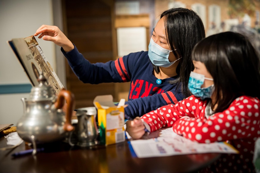 A mother shows her daughter a picture in a book in the Museum's Revolution Place.