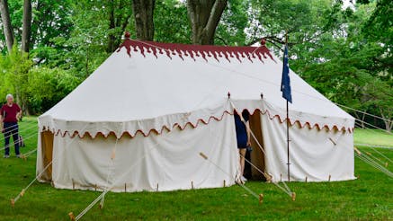 This image shows the handsewn replica linen tent with a silk replica commander in chief standard out front at Morristown National Historical Park.