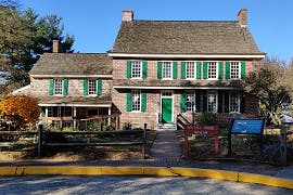 This image shows the Whitall house at Red Bank Battlefield with stone exterior and green shutters.