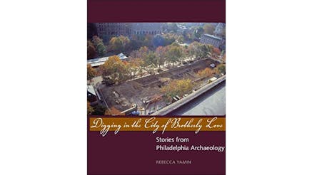 This image depicts the book cover of Digging in The City of Brotherly Love by Rebecca Yamin. The cover is a photo of a Philadelphia park in the fall. The top and bottom of the book cover are purple. The title of the book is written in front of a yellow strip.